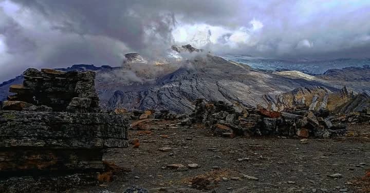 Terreno rocoso y estratificado con formaciones y suelo árido bajo cielo nuboso.